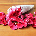 Red rose petals on a table, cones not included.