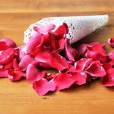 Red rose petals on a table, cones not included.